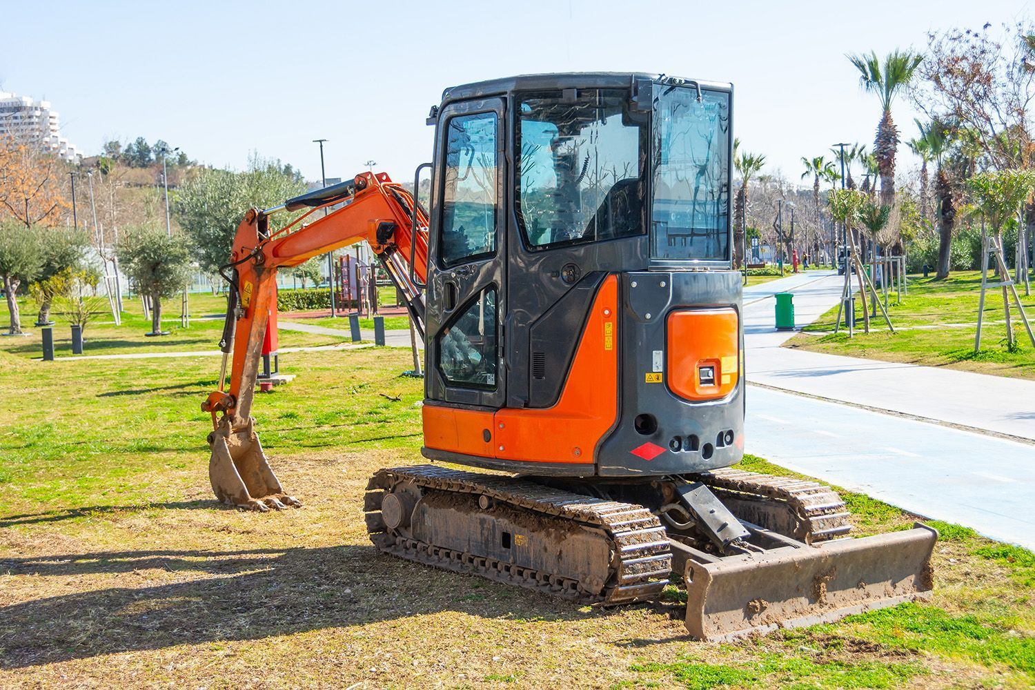 a small excavator is parked in the grass in a park .