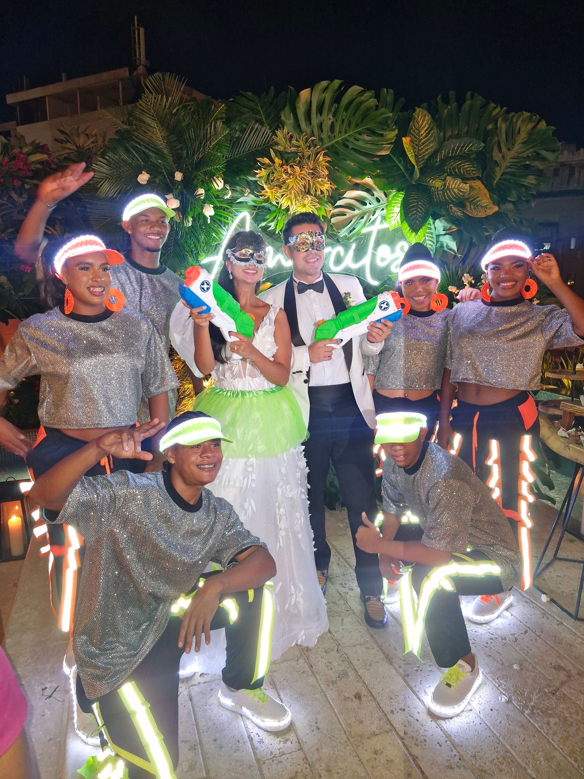 Una novia y un novio posan para una fotografía con un grupo de bailarines.