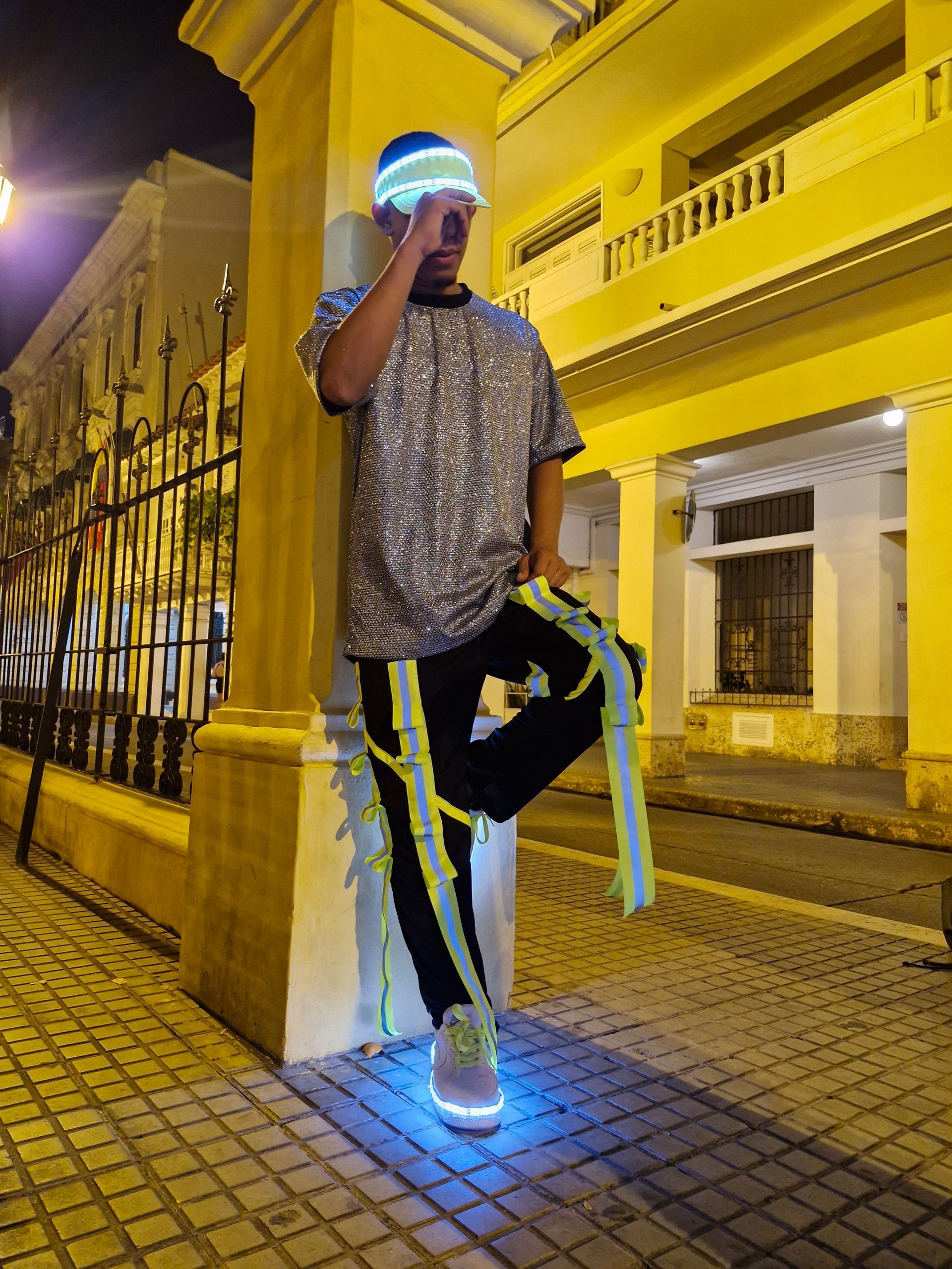 Un hombre que lleva zapatos que brillan en la oscuridad está parado frente a un edificio.