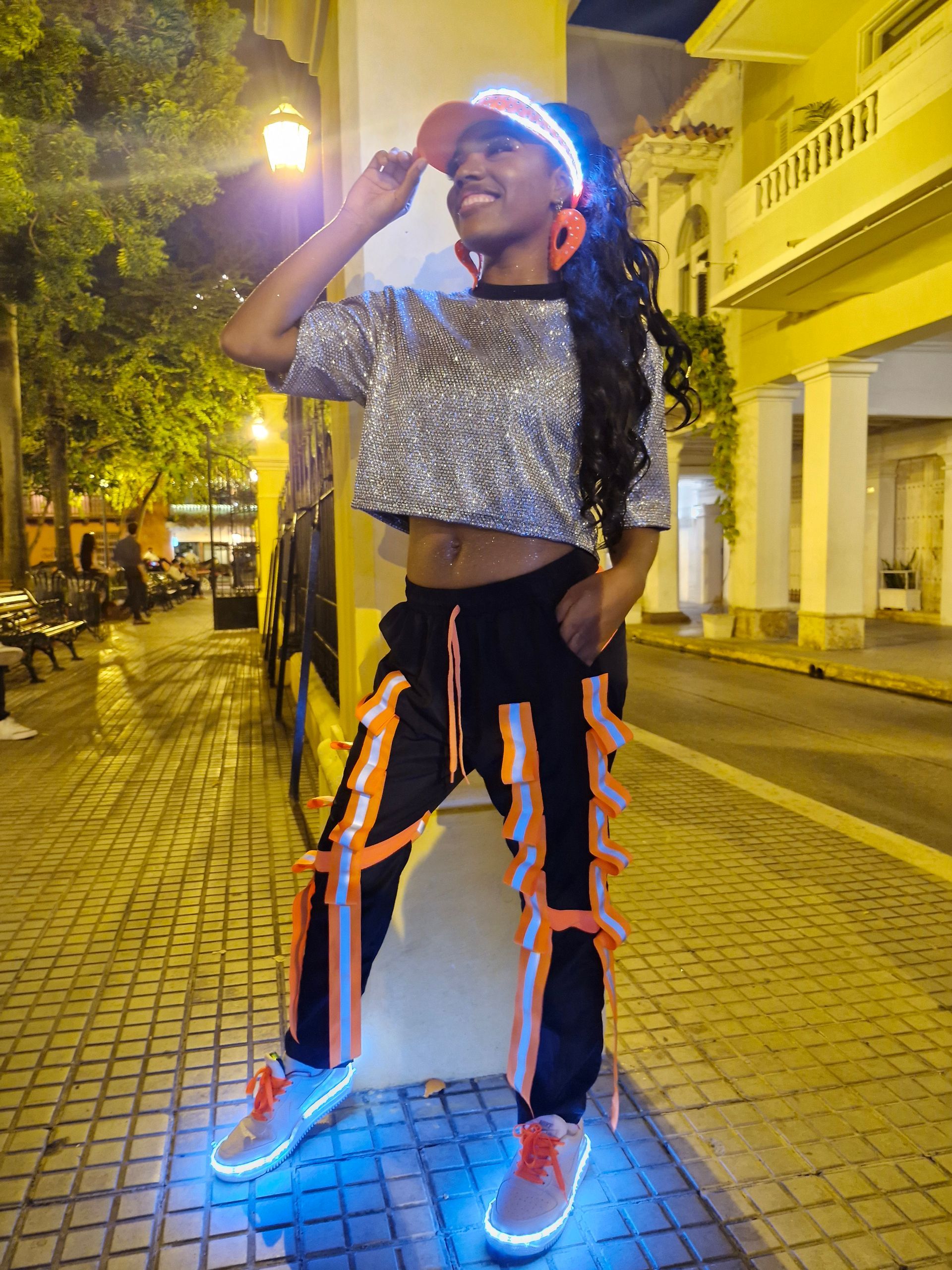 Una mujer está parada en una acera usando zapatos que brillan en la oscuridad.