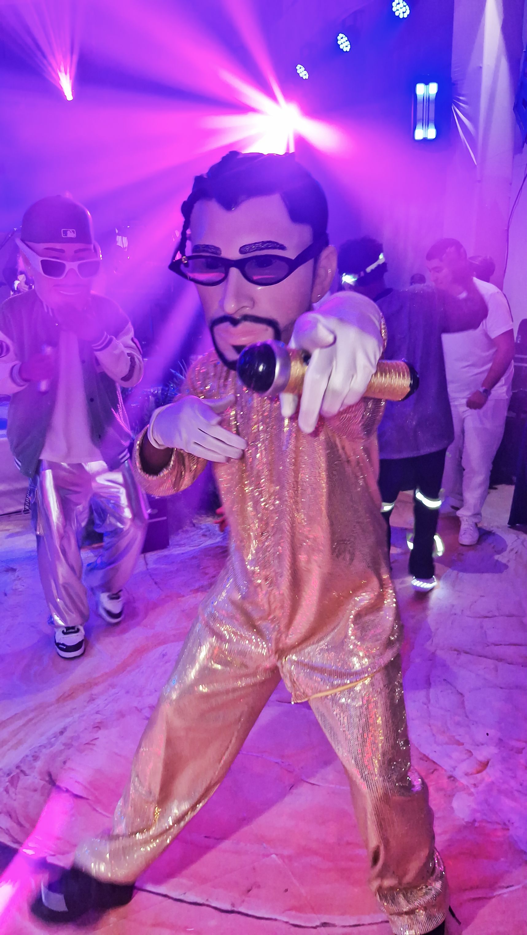 Un hombre disfrazado de mascota está cantando en un micrófono en una fiesta.