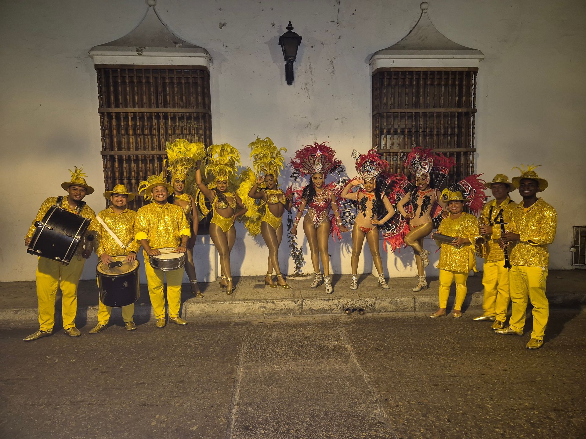 Un grupo de personas con disfraces coloridos están de pie frente a un edificio.