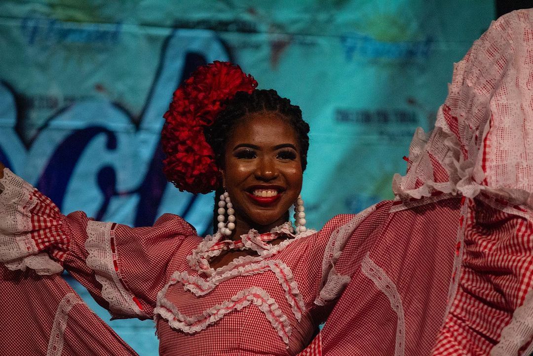 Una mujer con un vestido rojo y blanco está bailando en un escenario.
