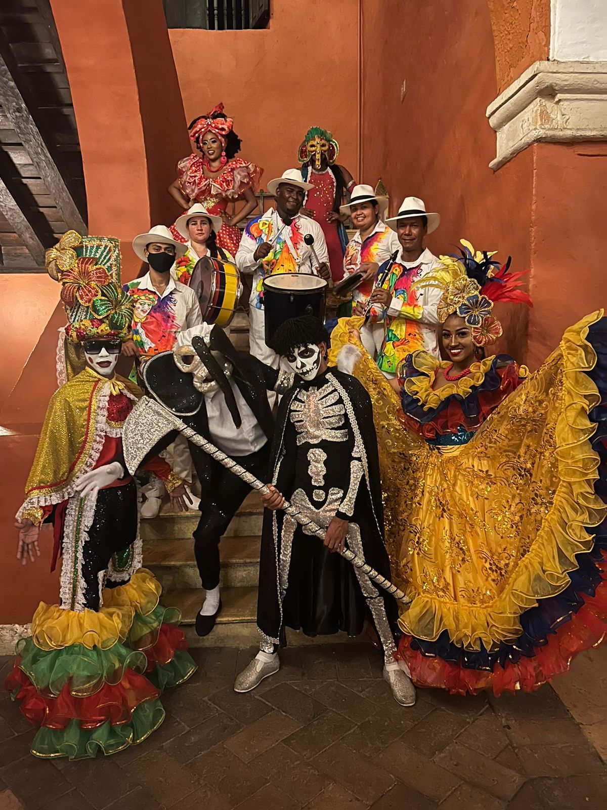 Un grupo de personas vestidas con trajes coloridos están de pie en un conjunto de escaleras.