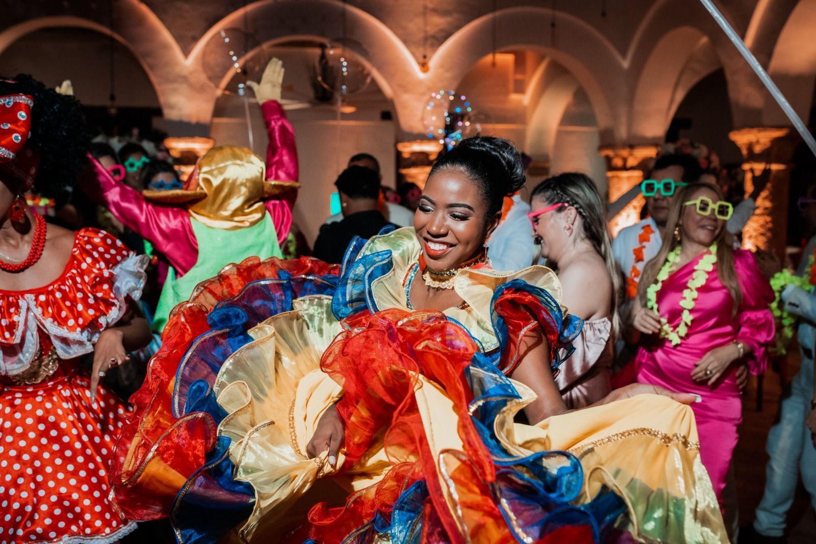 Una mujer con un vestido colorido está bailando con un grupo de personas en una fiesta.