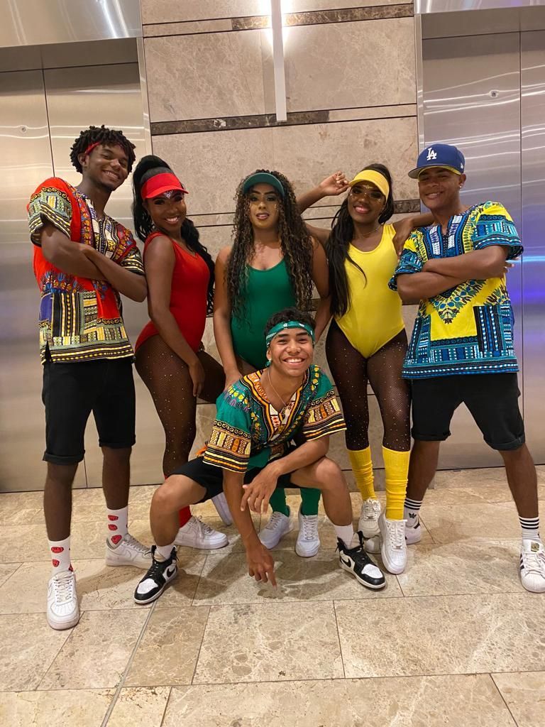 Un grupo de personas vestidas con trajes de los años 80 posan para una fotografía.