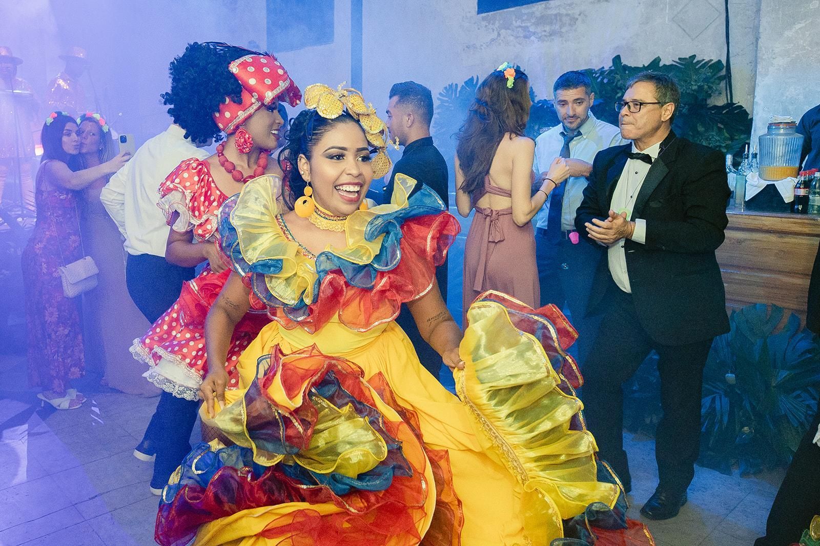 Una mujer con un vestido colorido está bailando con un grupo de personas en una fiesta.