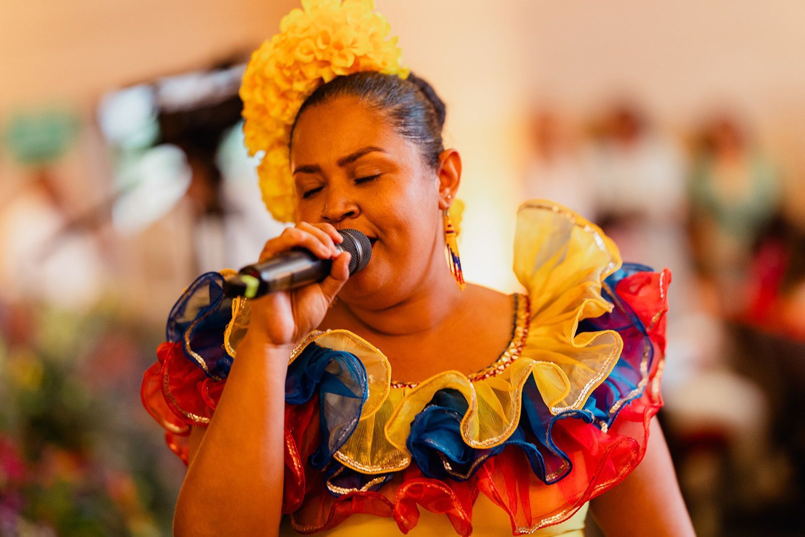 Una mujer con un vestido colorido está cantando en un micrófono.