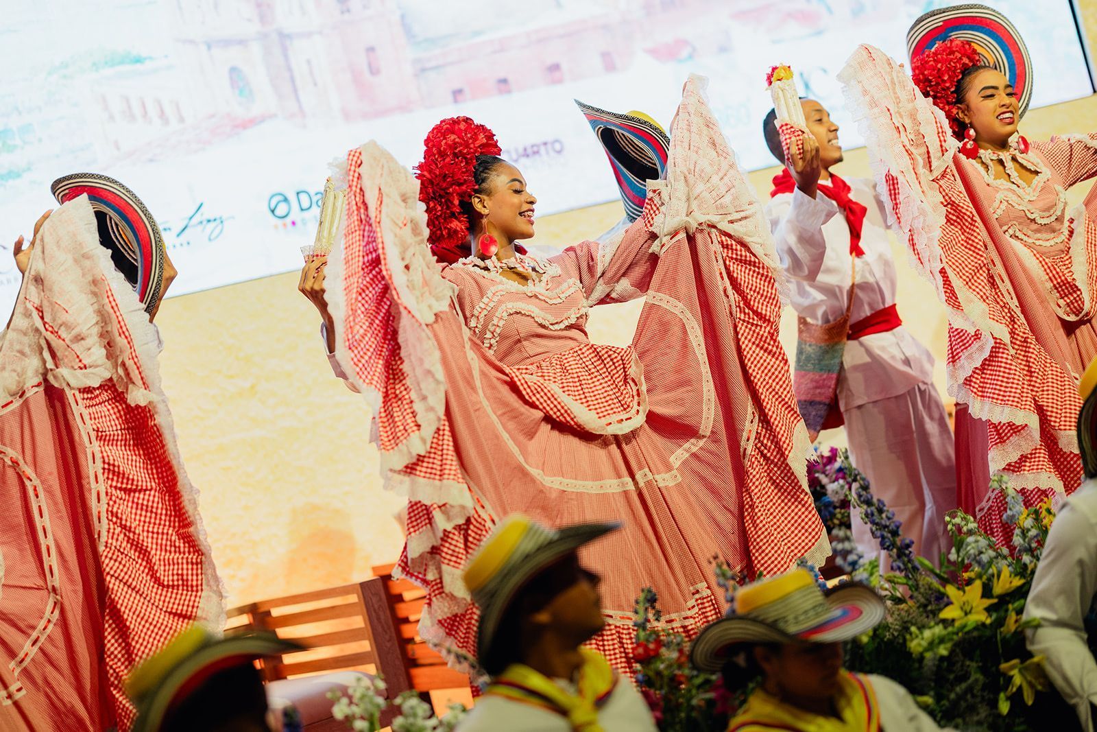 Un grupo de personas con ropa tradicional están bailando en un escenario.