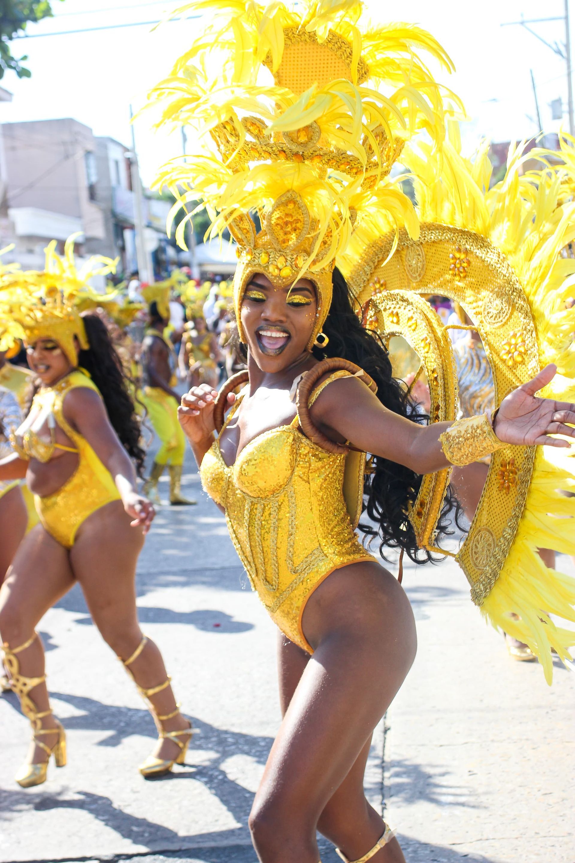 Una mujer con un traje amarillo está bailando en un desfile.