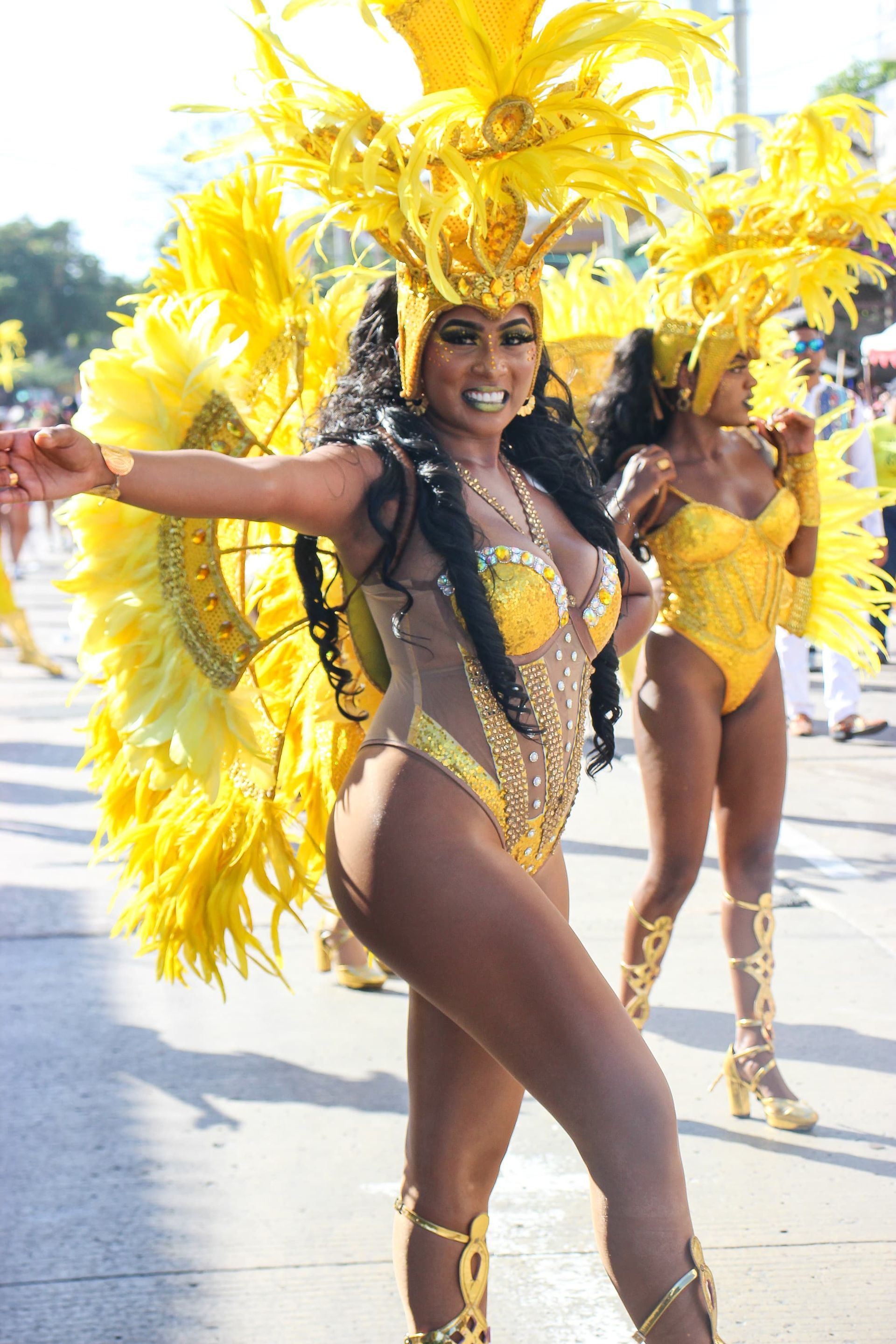 Una mujer con un traje amarillo está bailando en un desfile.