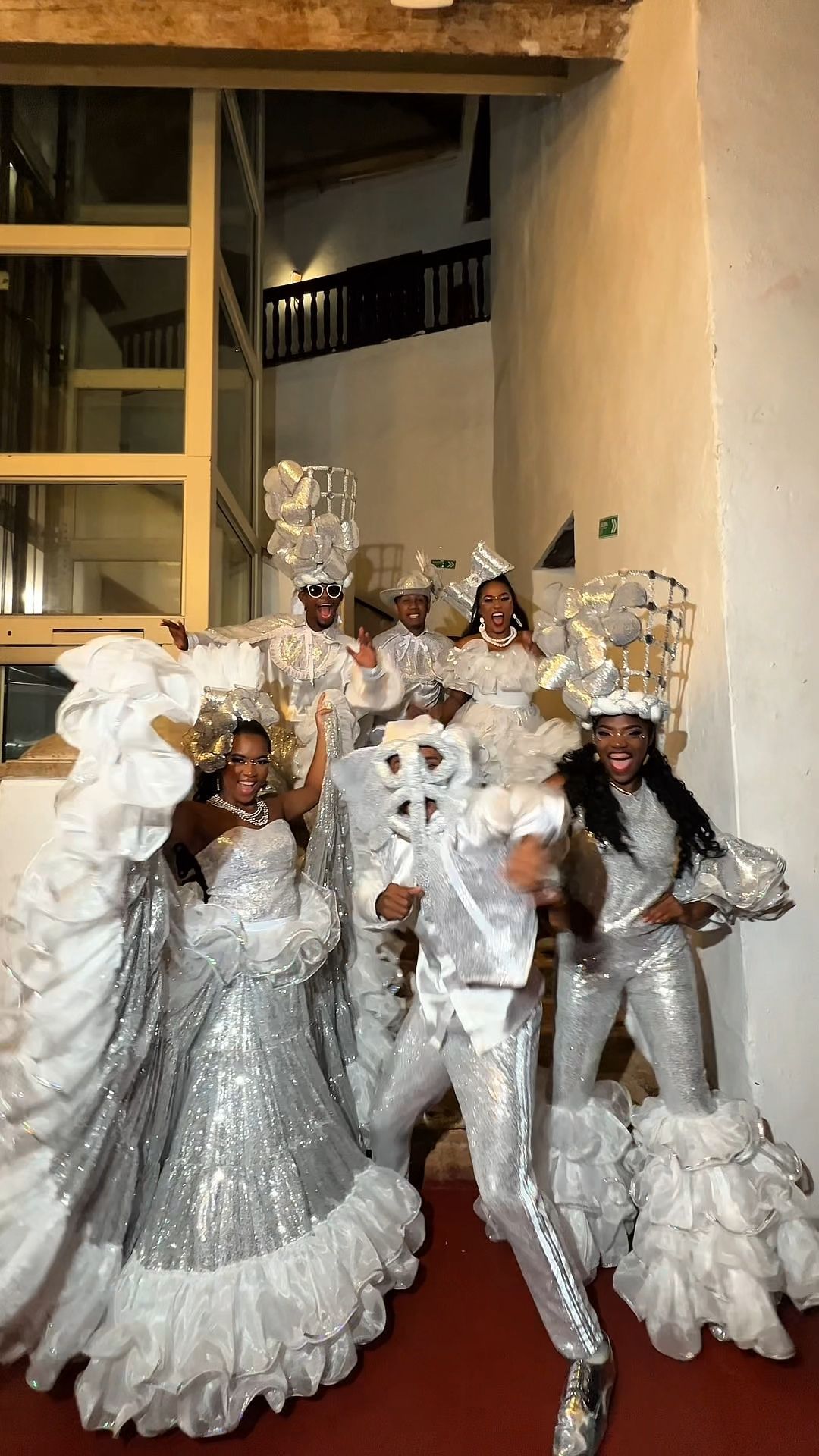 Un grupo de personas vestidas de blanco están bailando sobre una alfombra roja.