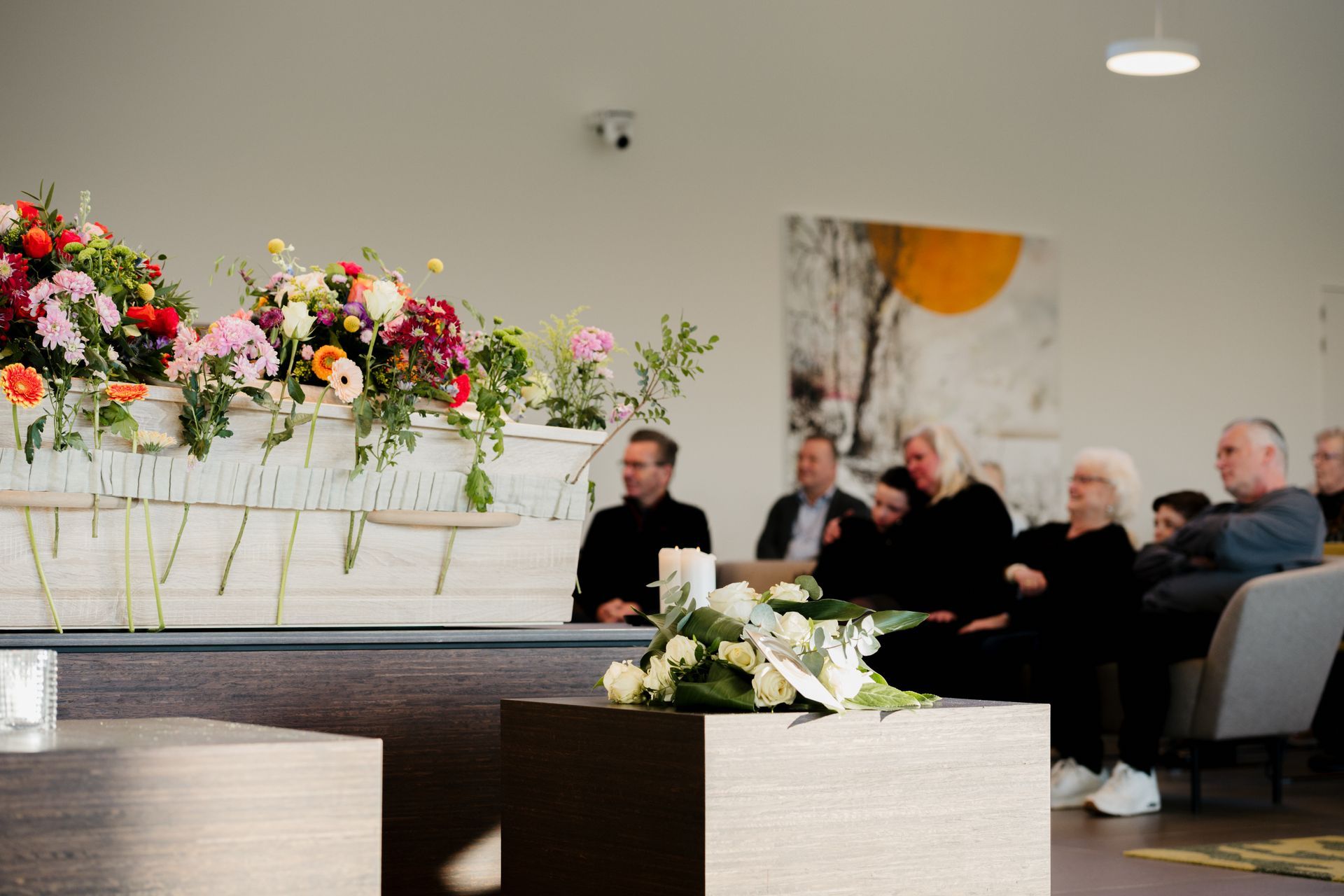 Een groep mensen zit in een kamer met bloemen voor zich.