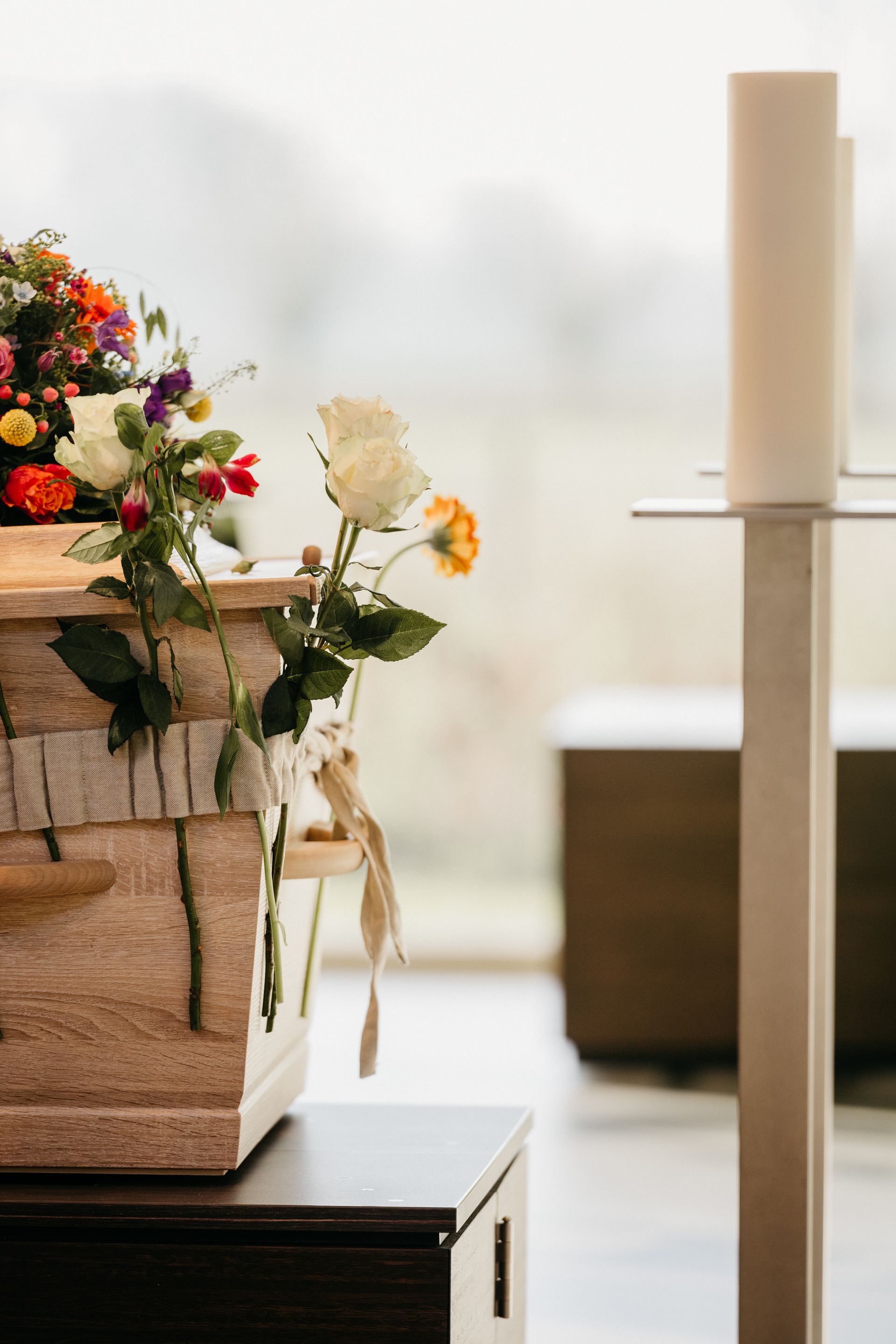 Op een tafel staat een doodskist met bloemen erop.