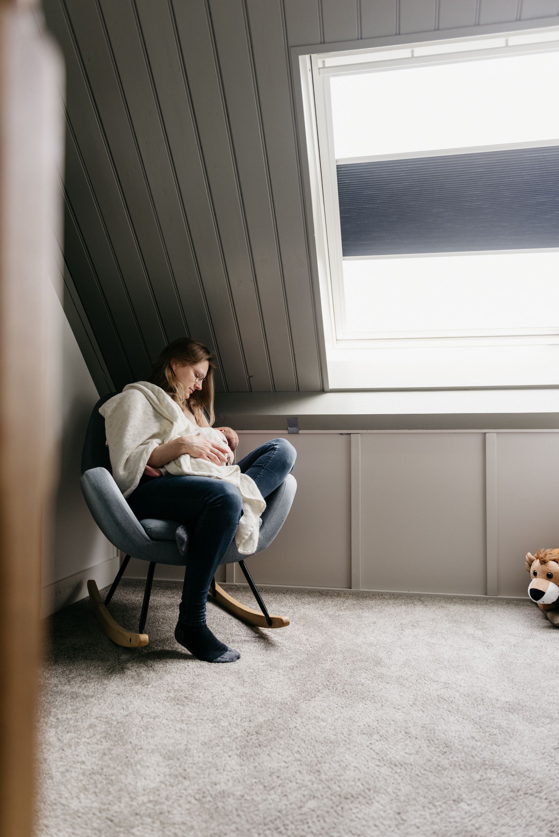 Een vrouw zit in een schommelstoel en geeft haar baby borstvoeding.
