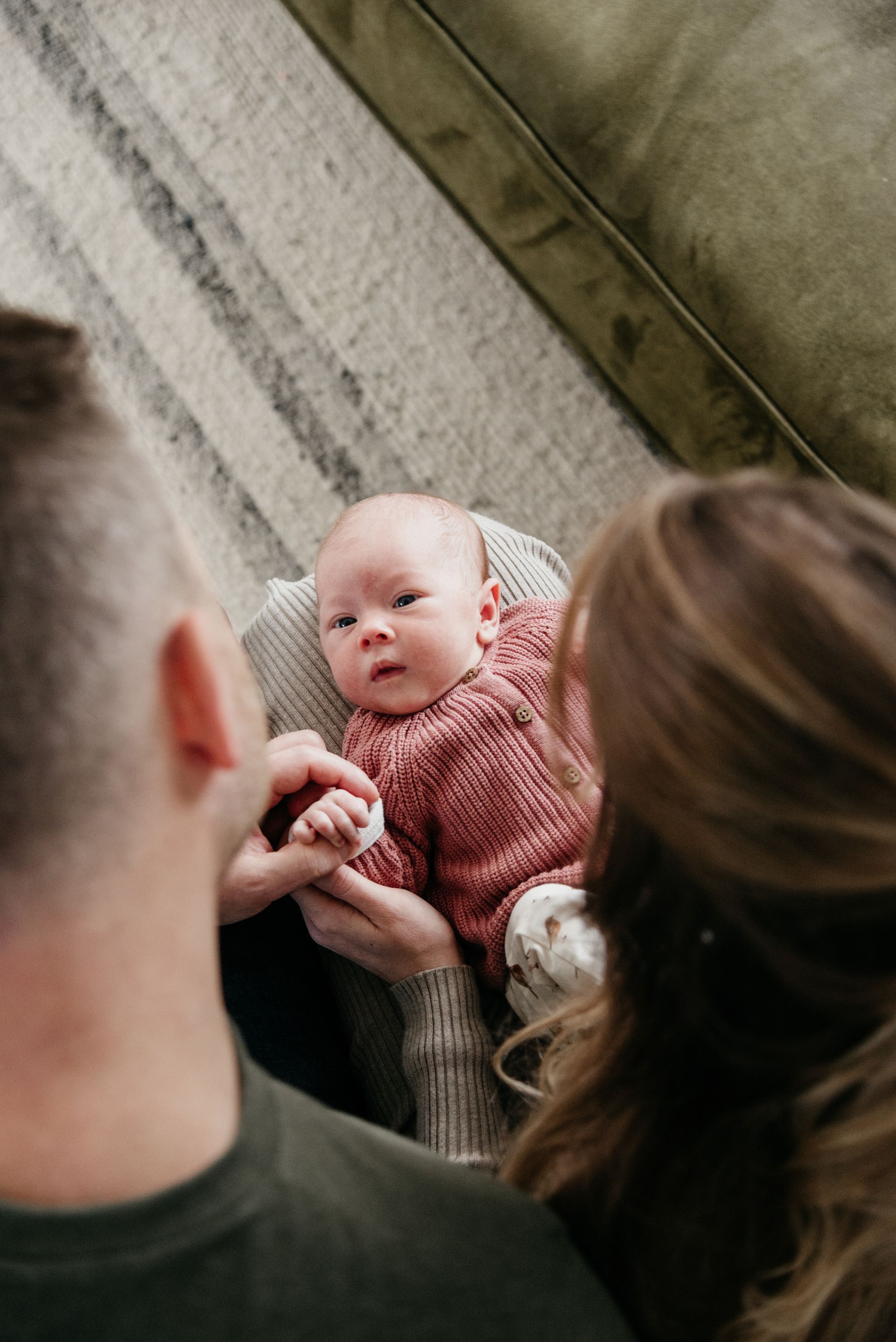 Een man en een vrouw zitten op een bank en houden een baby vast.