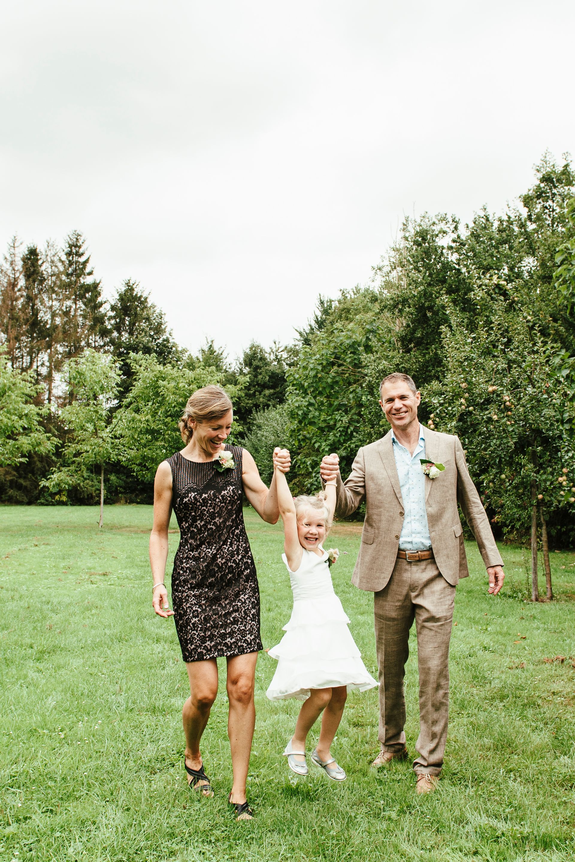 Een man en een vrouw lopen met een klein meisje in een veld.