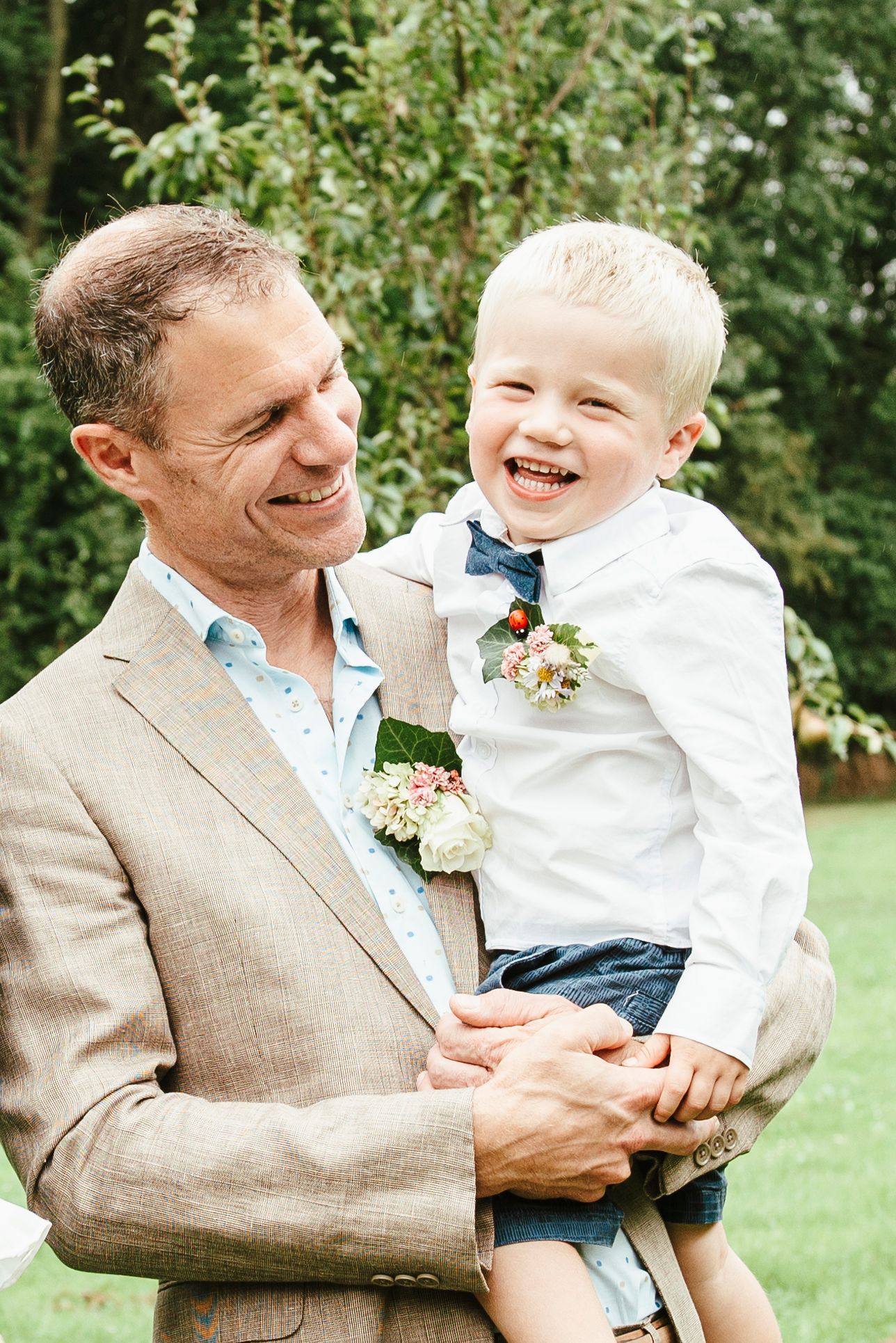 Een man in pak houdt een jongetje in zijn armen.