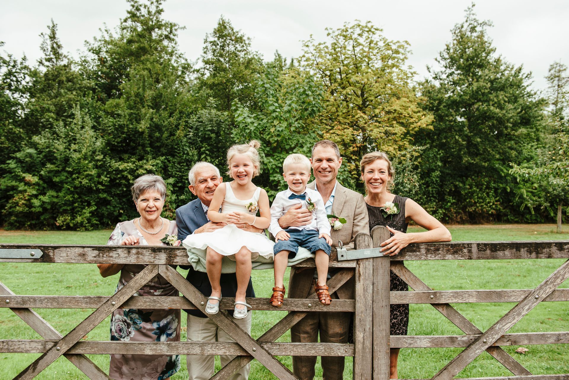 Een gezin poseert voor een foto terwijl ze op een houten hek zitten.