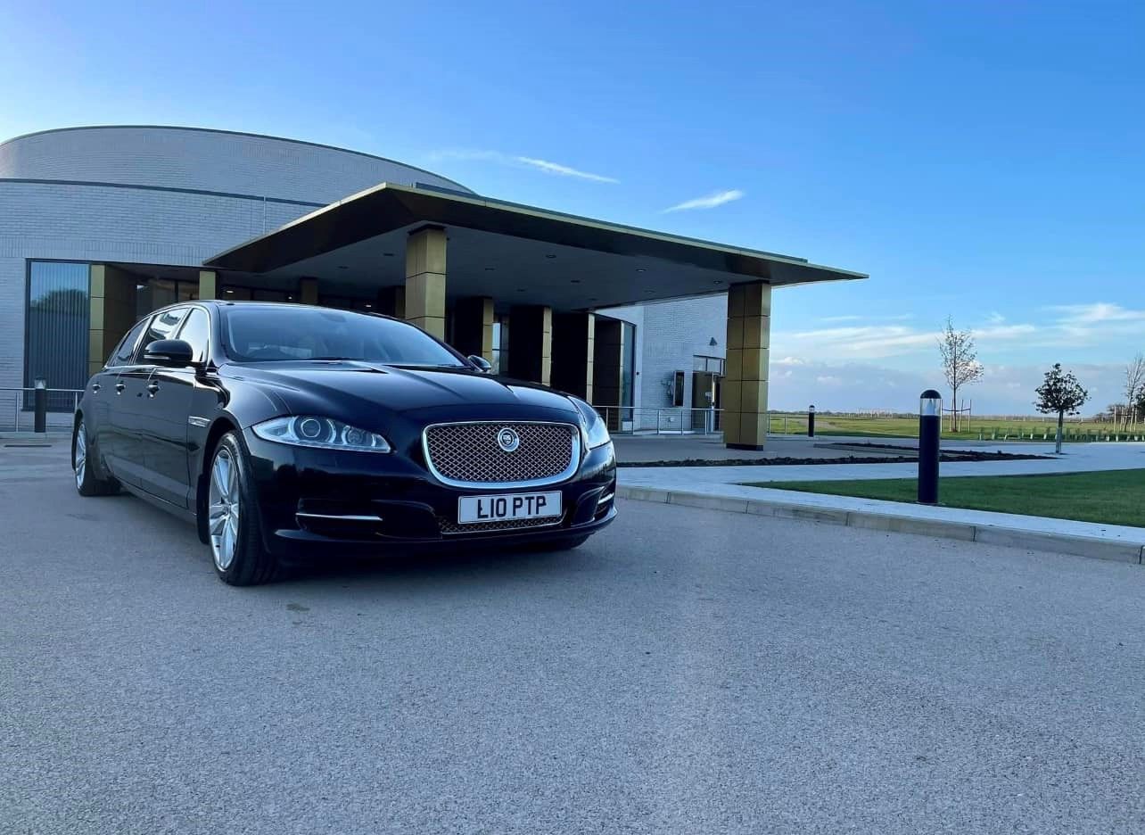 Black Jaguar sedan parked in front of a modern building on a sunny day.