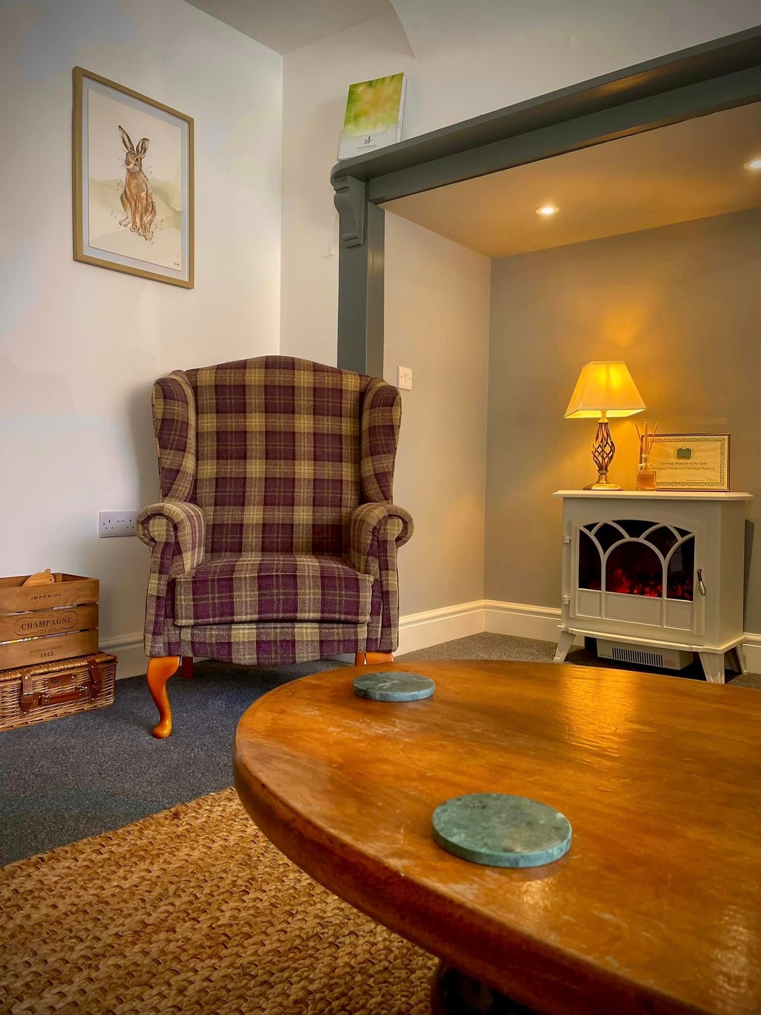 A cozy living room with a plaid armchair, wooden coffee table, and a fireplace.