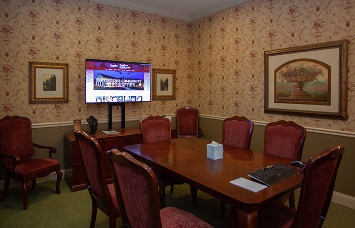 A conference room with a large table and chairs and a flat screen tv.