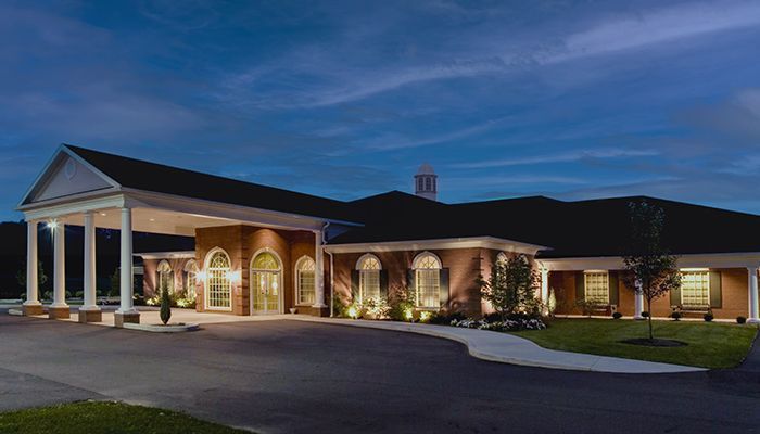 A large brick building with a driveway and trees in front of it