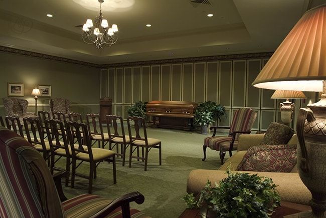 A room with rows of wooden chairs and a piano in the background.