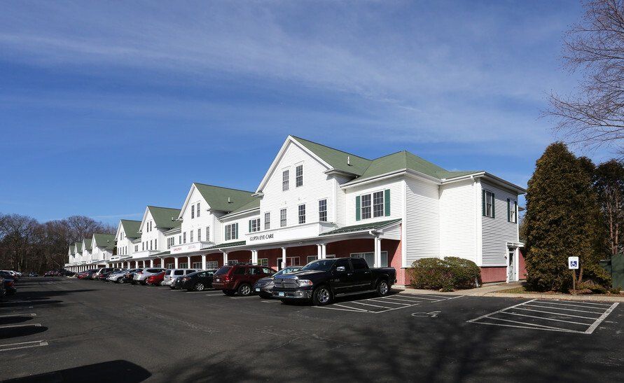 A row of white houses with green roofs are lined up in a parking lot.