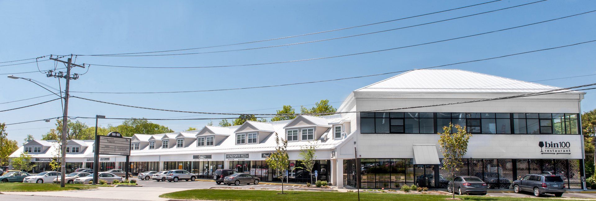 A large white building with a white roof and a lot of cars parked in front of it.
