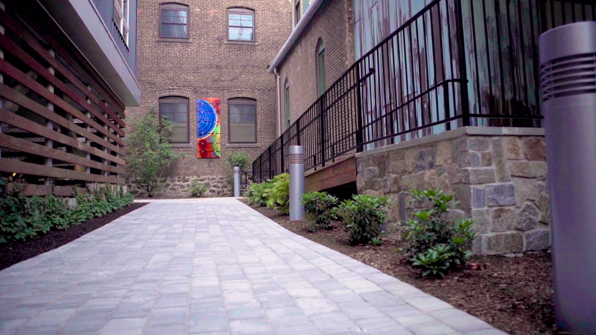 A brick walkway leading to a brick building with a fence.