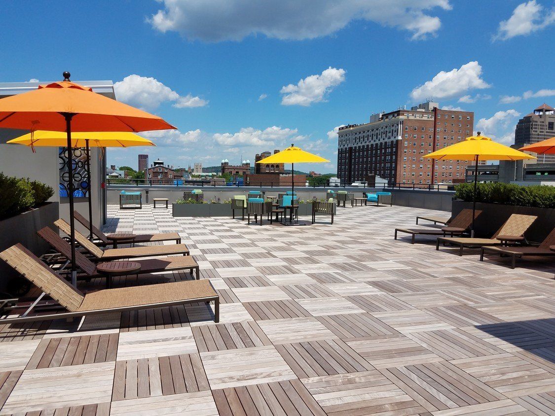 A rooftop patio with chairs and umbrellas on a sunny day