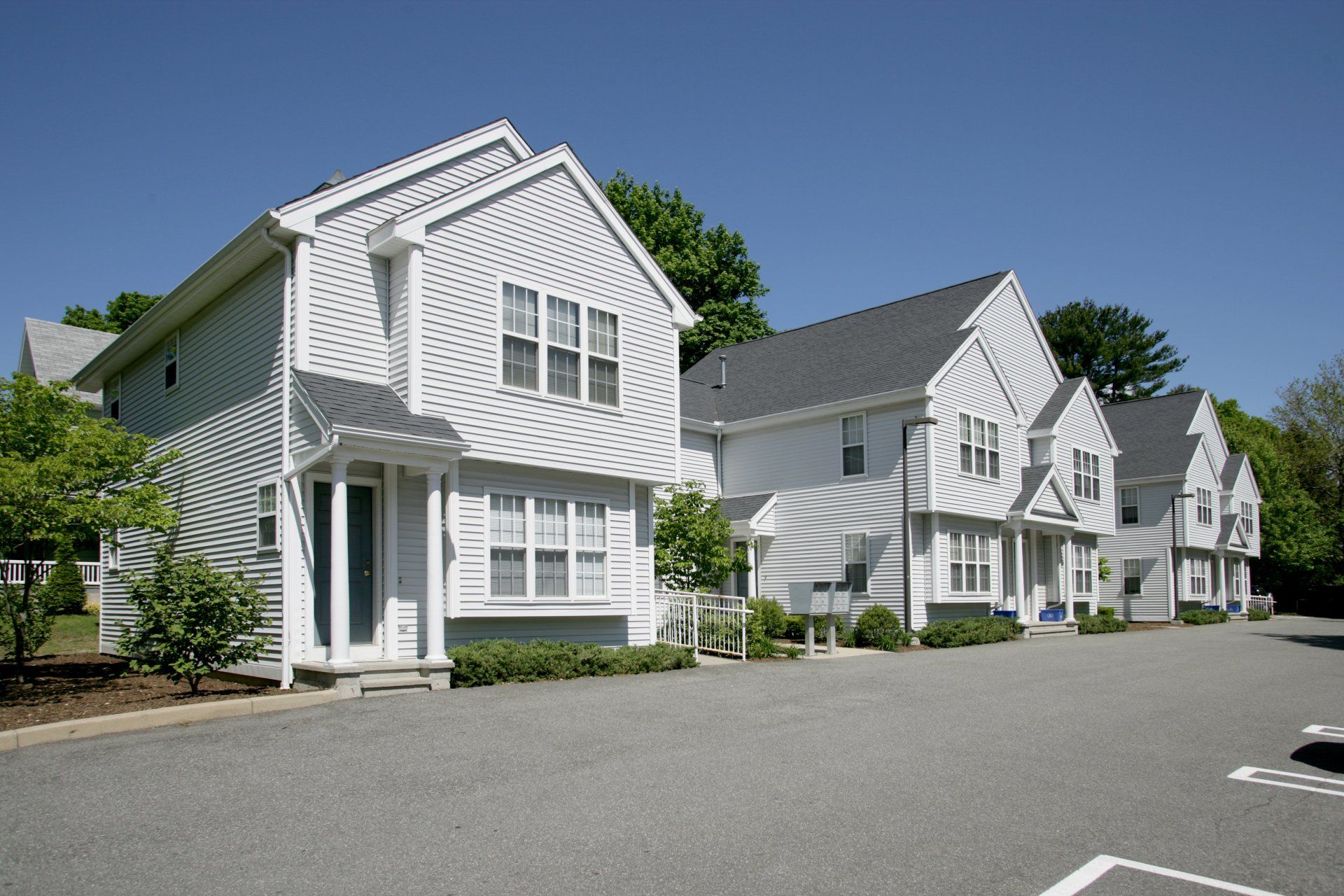 A row of white houses with a parking lot in front of them