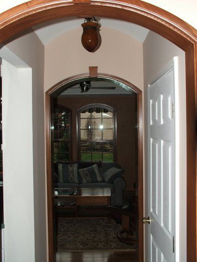 A hallway with a wooden archway leading to a living room