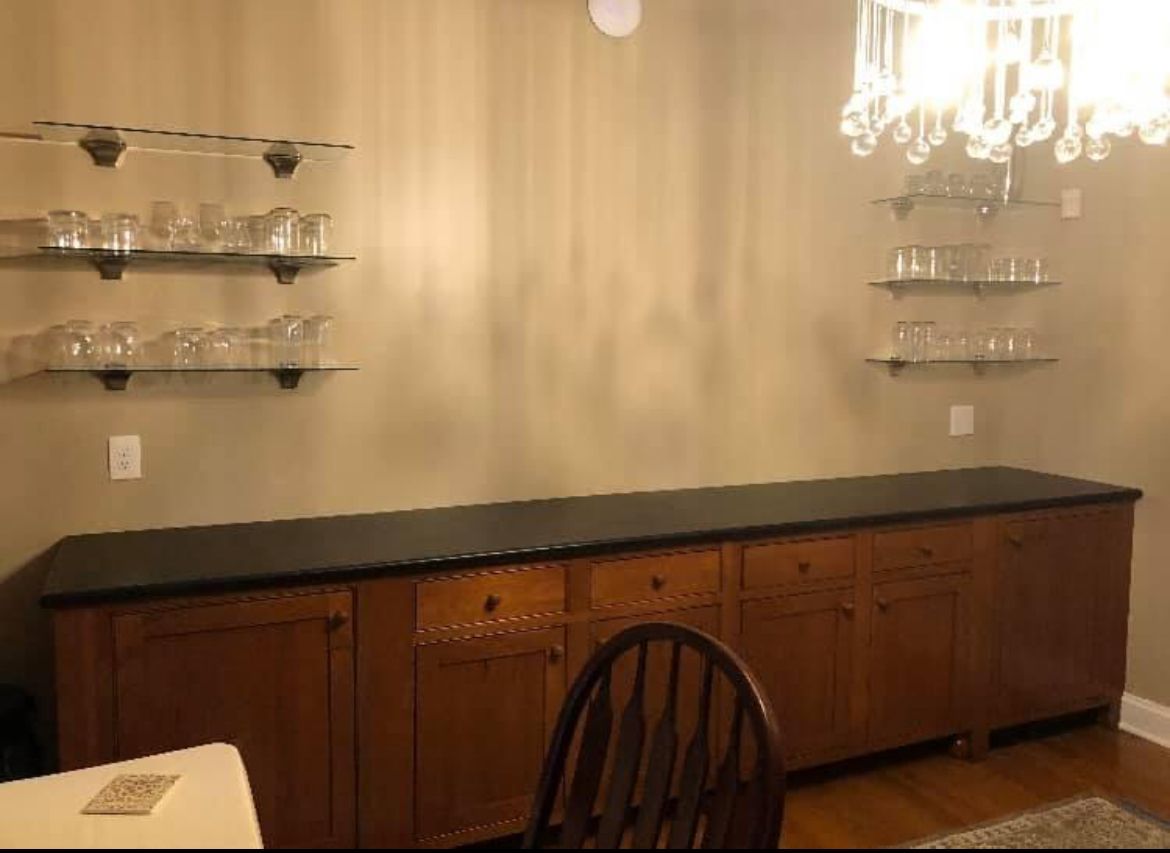 A dining room with a long counter and shelves filled with glasses.