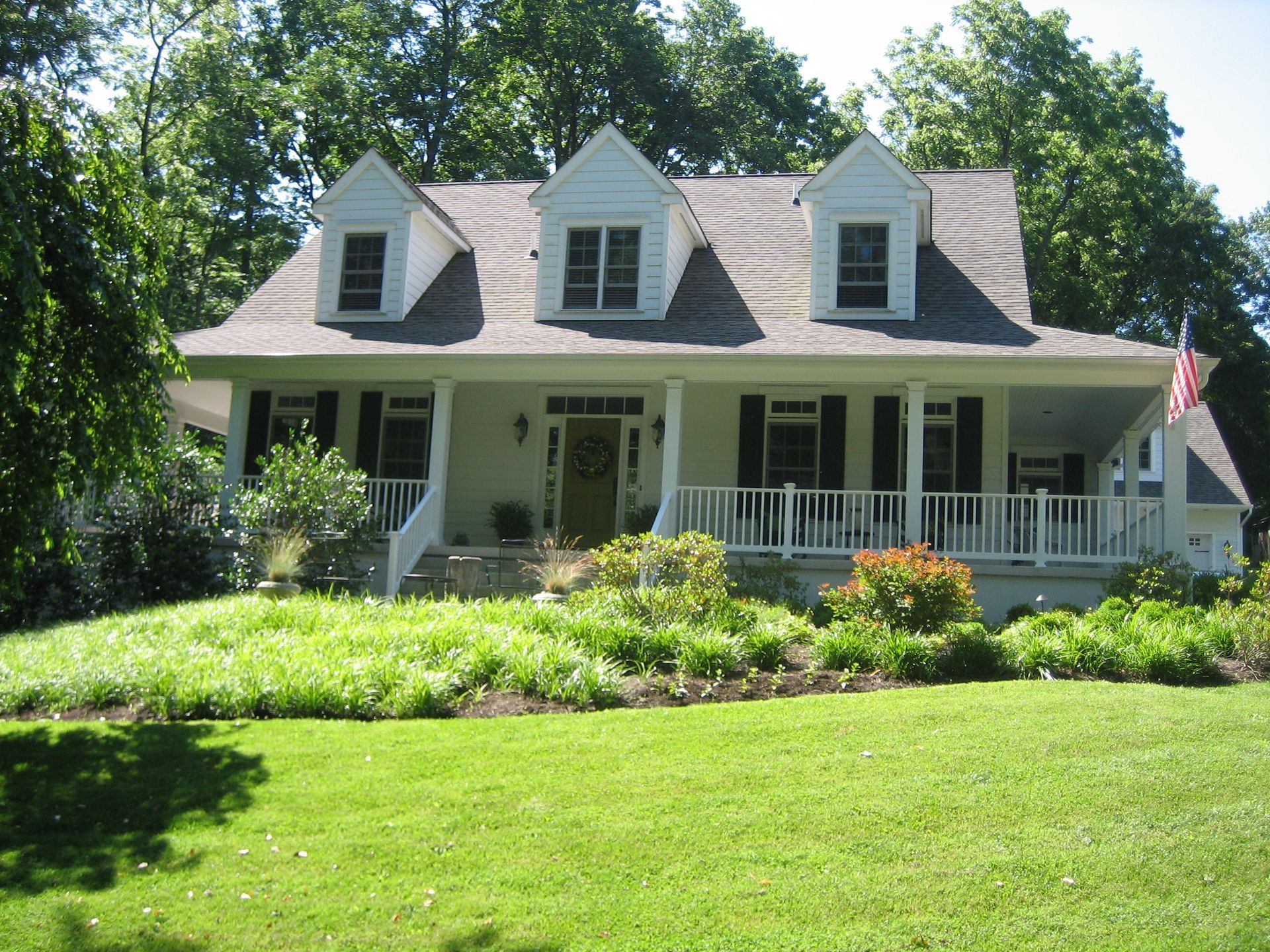 A white house with black shutters and a large porch