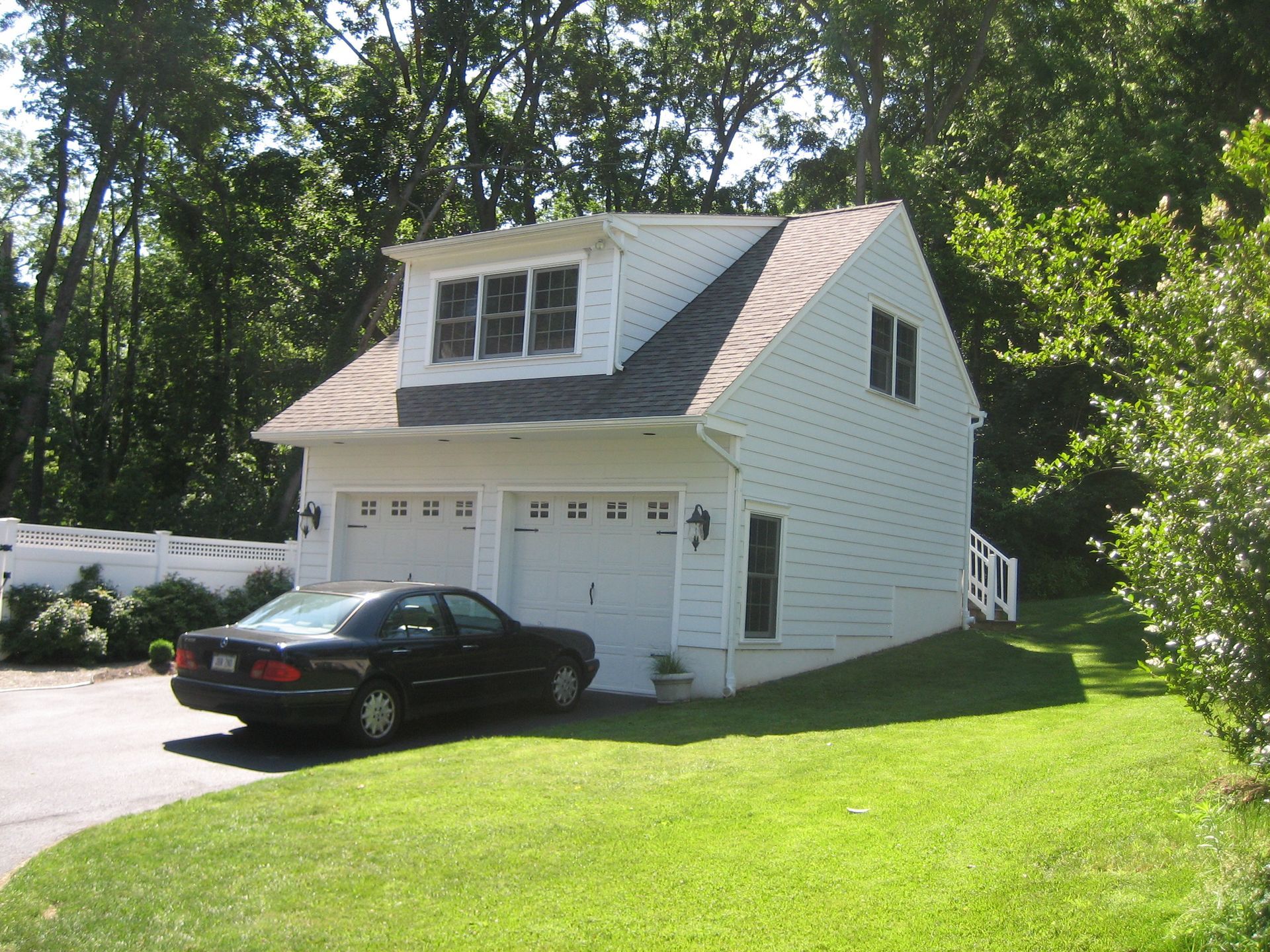 A black car is parked in front of a white garage