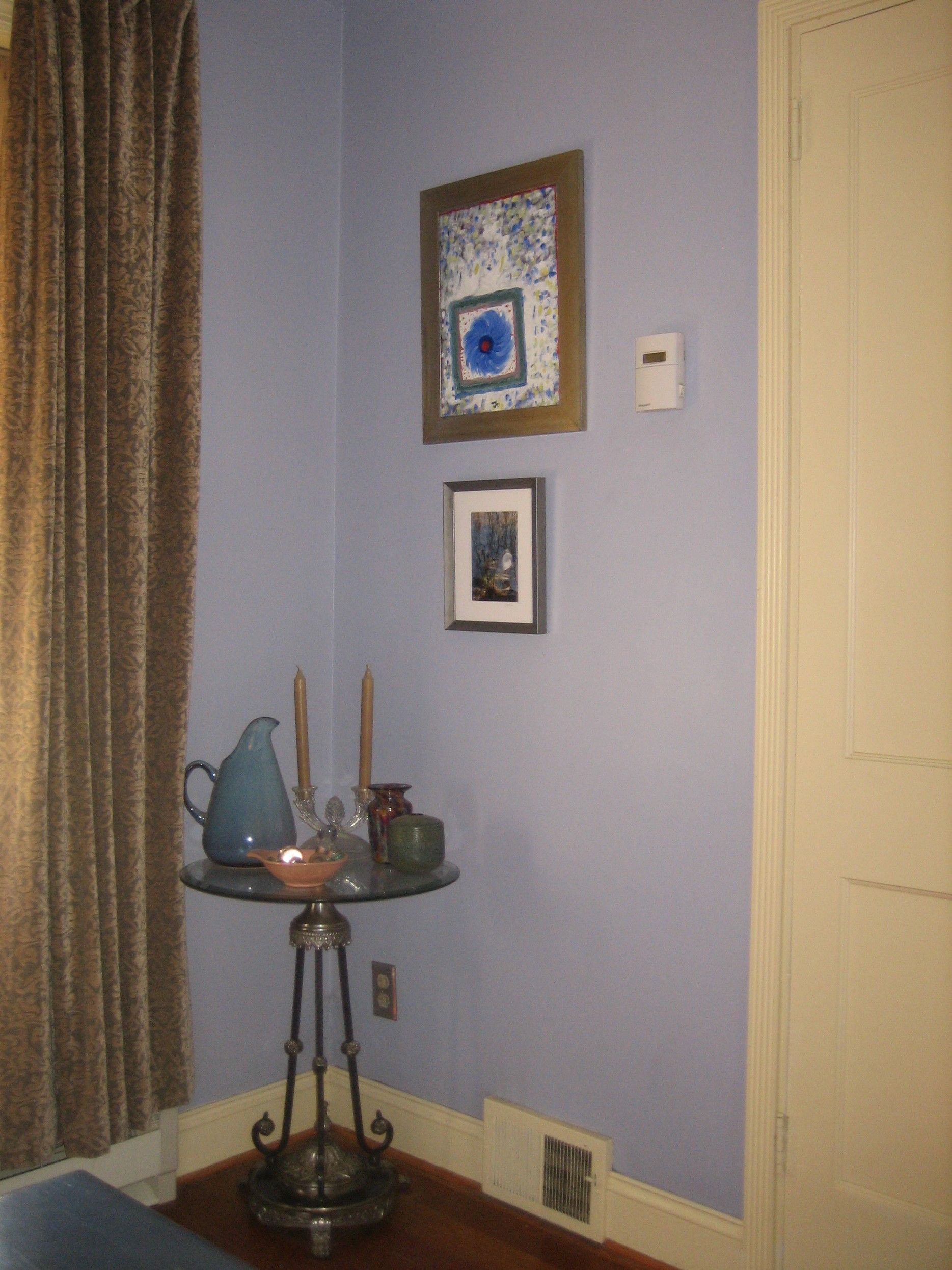 A corner of a room with a table and pictures on the wall