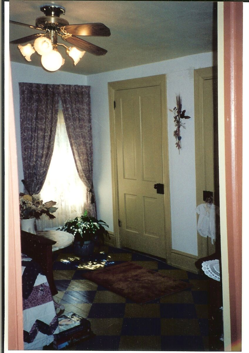 A room with a ceiling fan and purple curtains
