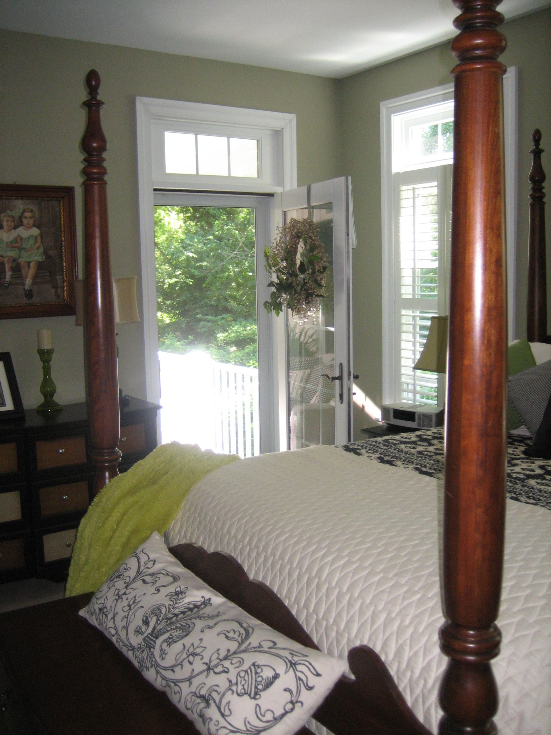 A bedroom with a four post bed and a sliding glass door
