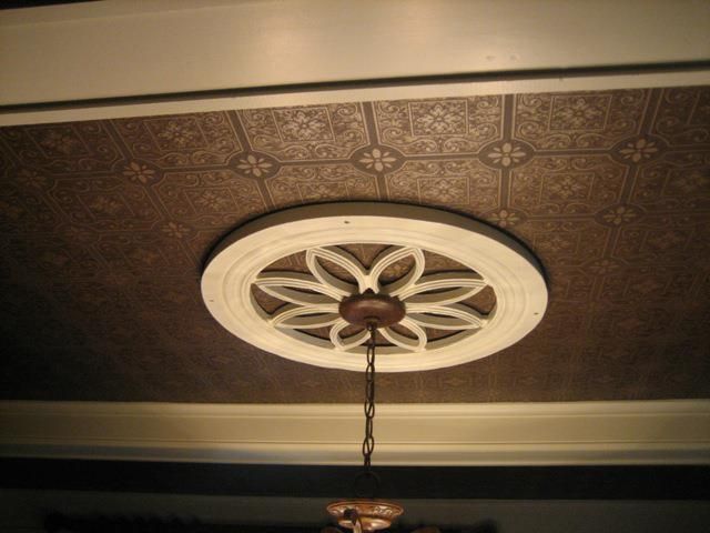 A chandelier is hanging from a ceiling with a flower design