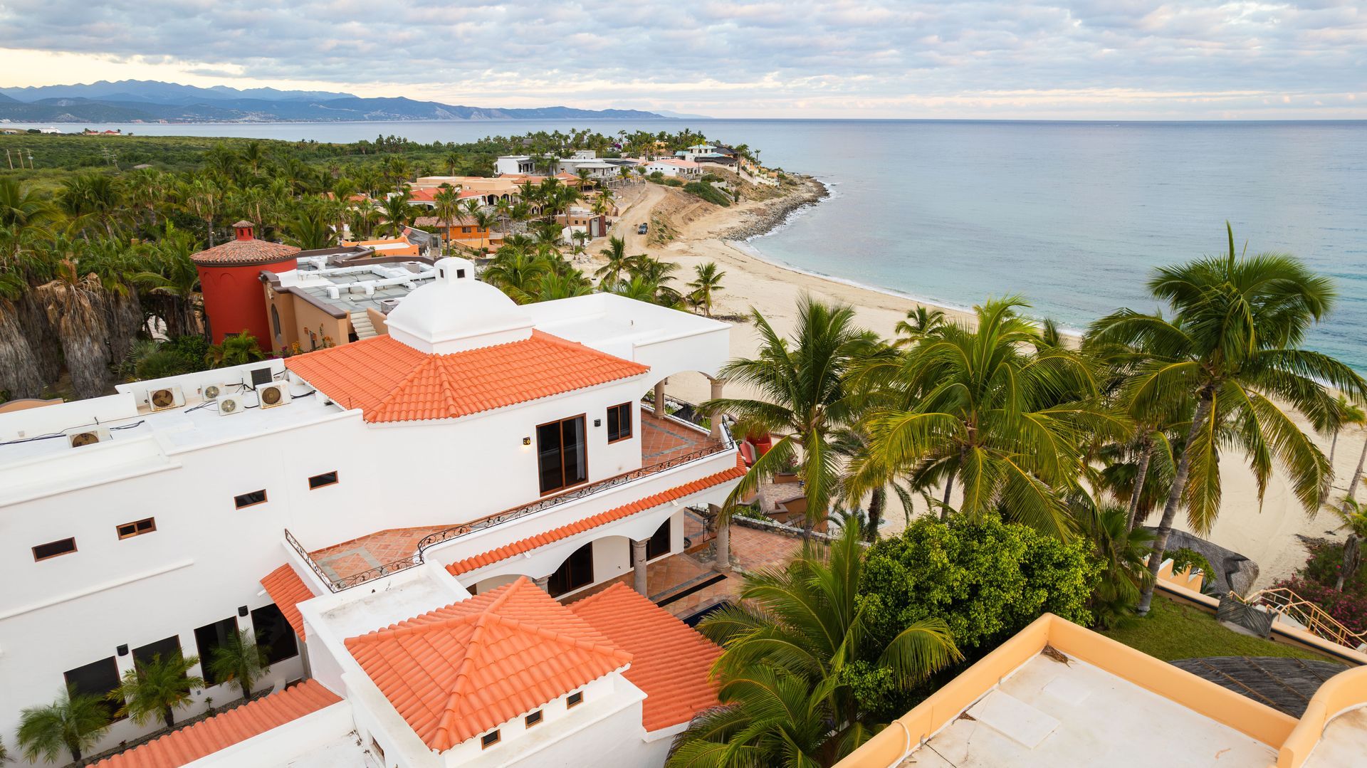 An aerial view of a large white building with a red tile roof