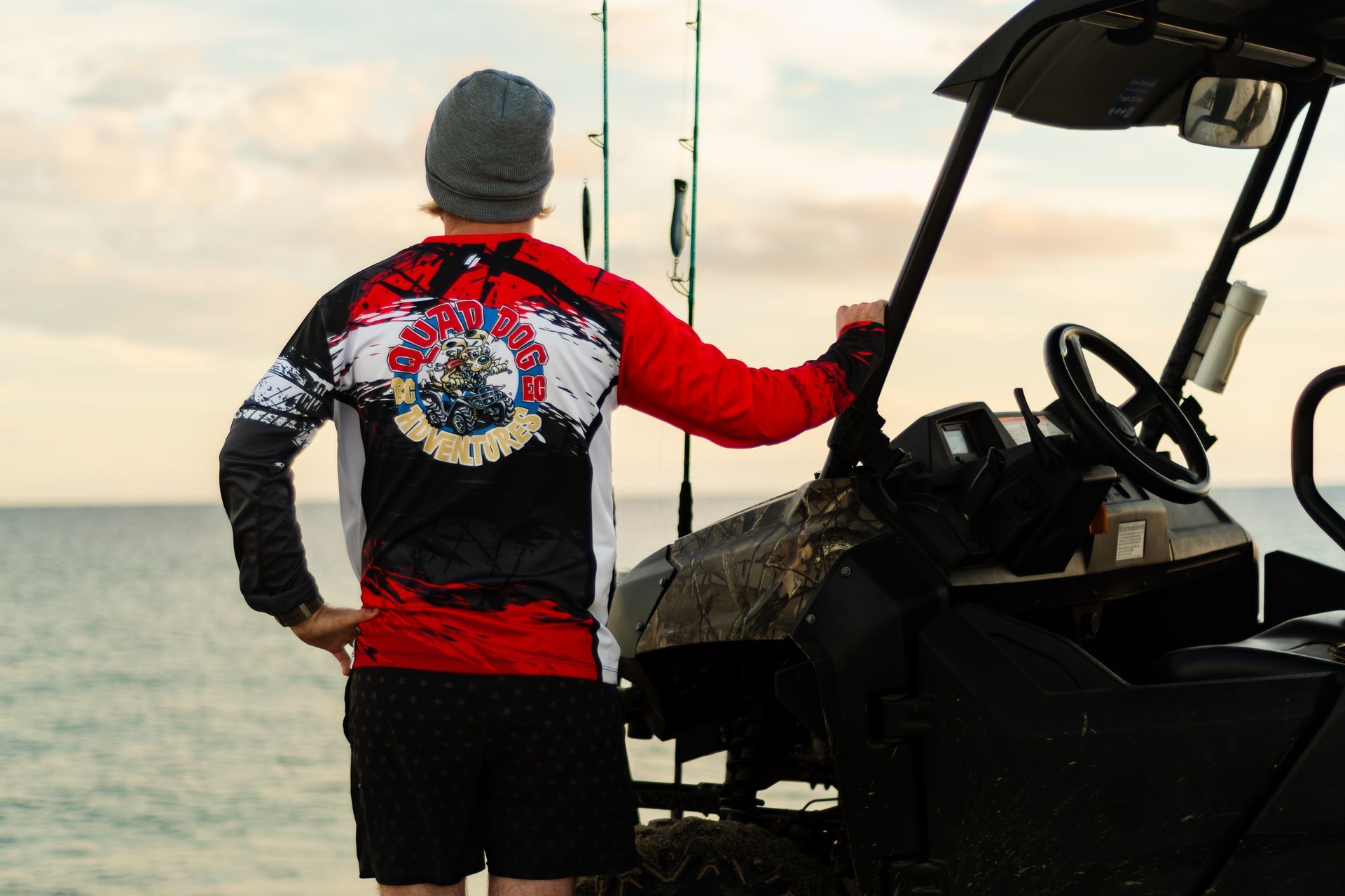 A man is standing next to a golf cart on the beach.