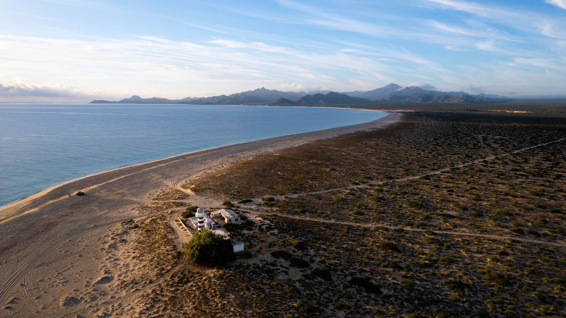 An aerial view of a beach with a car parked on the shore.