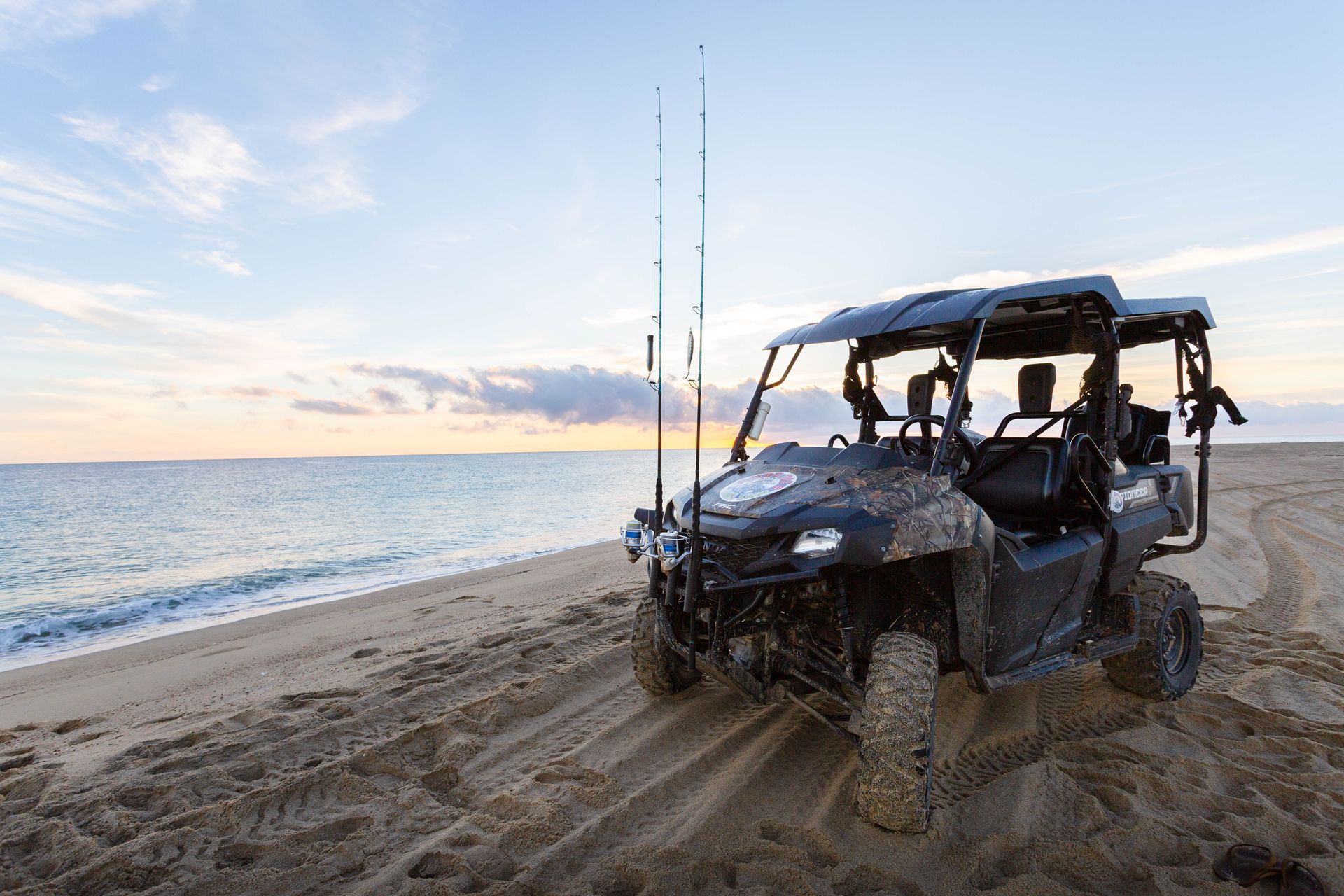 A atv is parked on the beach near the ocean.