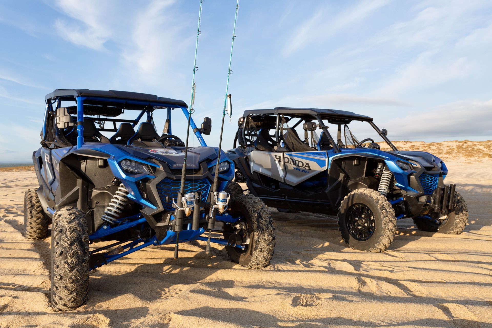 Two atvs are parked next to each other on a sandy beach.