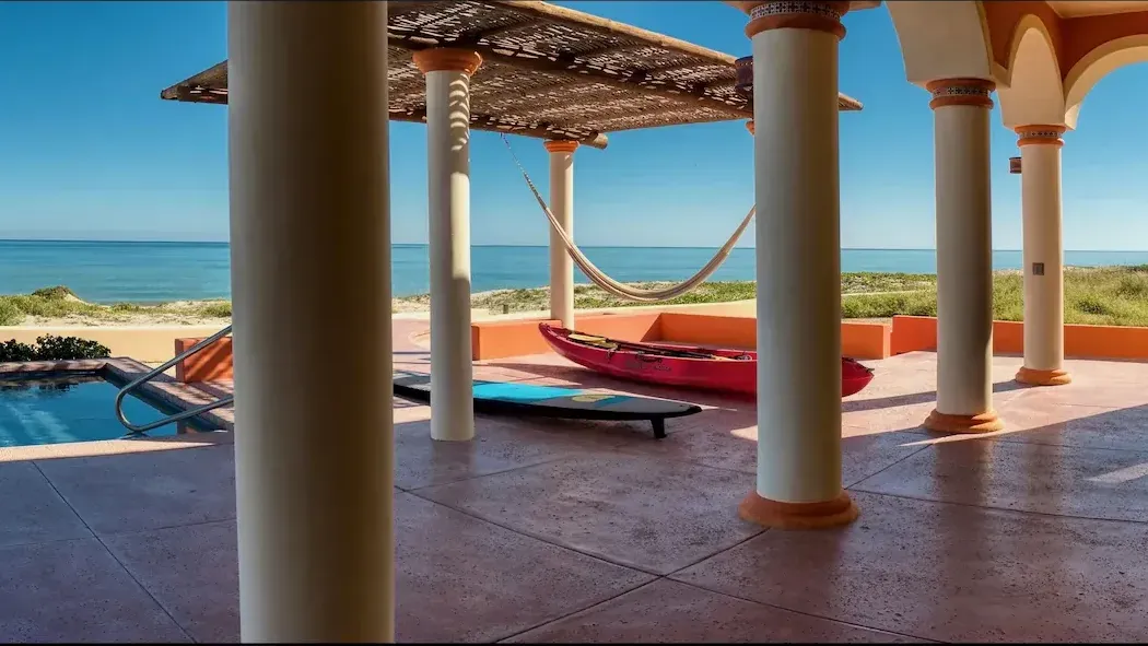 A patio with columns and a hammock overlooking the ocean