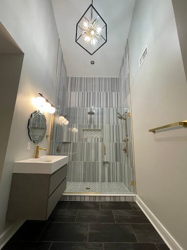 A bathroom with a walk in shower , sink and mirror.
