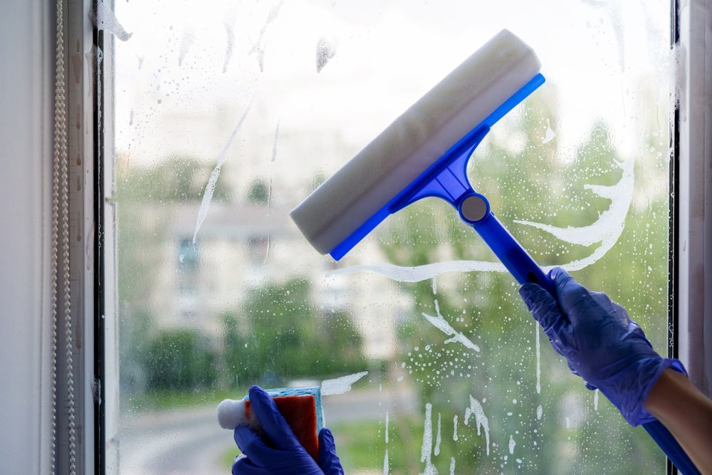 A Person is Cleaning a Window With a Squeegee — Reach 'N' Clean in Lismore, NSW