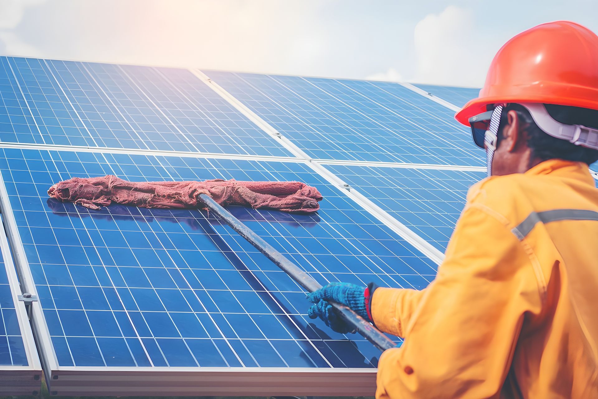 A Man is Cleaning Solar Panels With a Mop — Reach 'N' Clean in Byron Bay, NSW